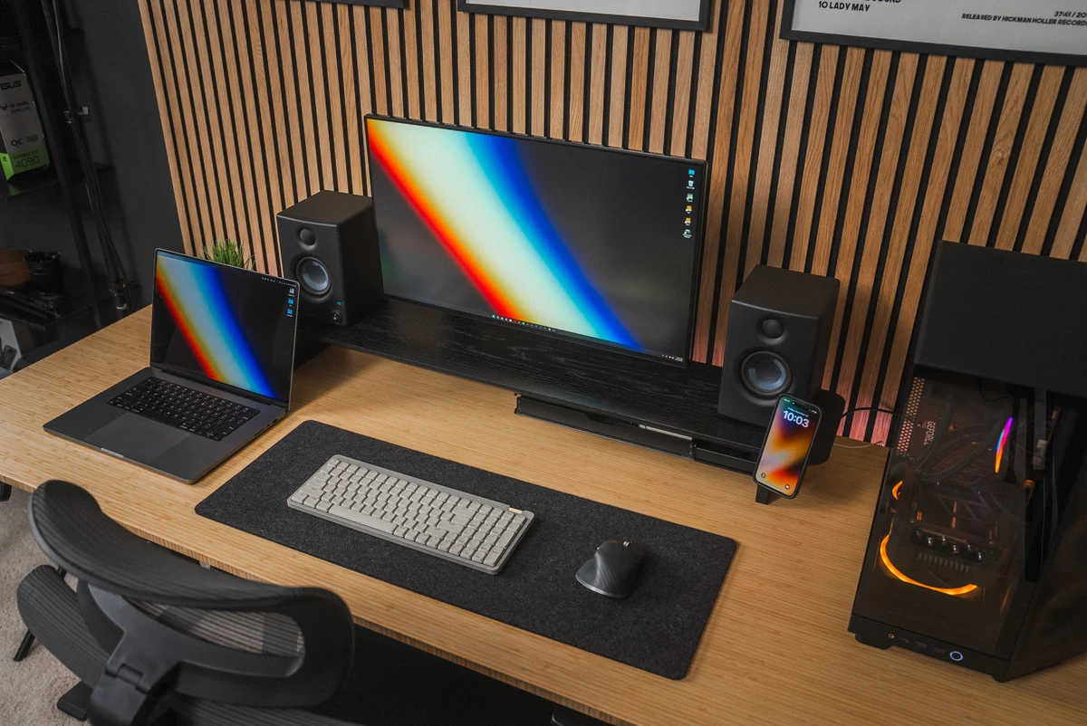 The desk setup with colorful wallpapers on the monitor, laptop, and phone