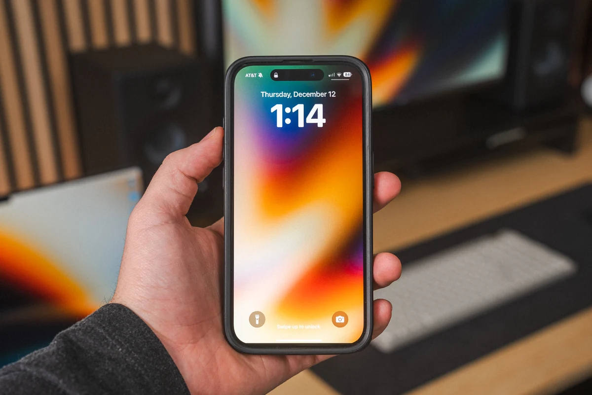 A hand holding a phone with a colorful Essential wallpaper